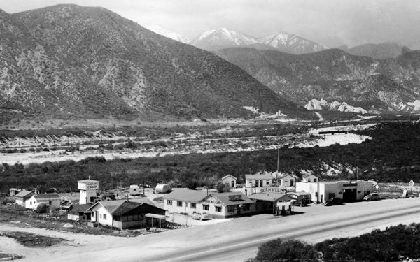 1940s Cajon Mt. Camp US66 in Cajon Junction black and white, highway 66 runs in front of cabins, campground, Cafe, Shell gas station and a garage, mountains beyond c.1940s