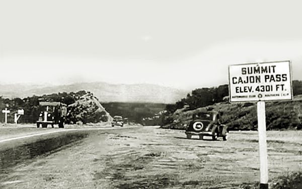 1930s Summit sign at Cajon Pass highway, vehicles, mountains in the distance, a cutting on a crest and sign reads SUMMIT CAJON PASS ELEV. 4301 FT. c.1930s