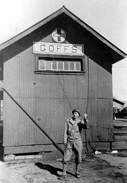 WWII view of Goffs black and white 1940s, soldier by building with corrugated steel walls sign reads GOFFS, US flag