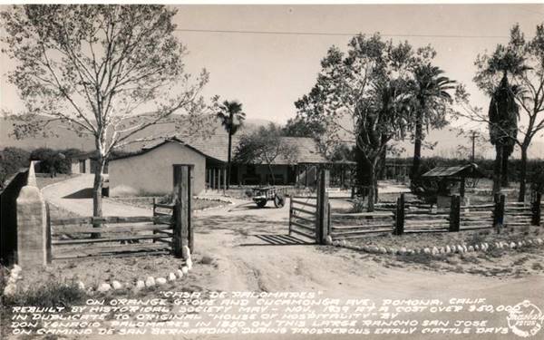 black and white photo 1940s postcard of a ranch, with fence, cart and text explaining it