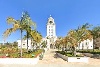 white building, tower in center, facing plaza with palm trees
