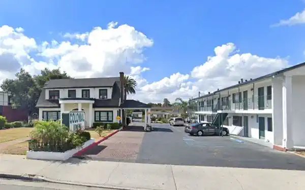 Azusa CA The Colonial Inn on Route 66 left, 2-story gable roof house. Sign of COLONIAL INN, right units, cars