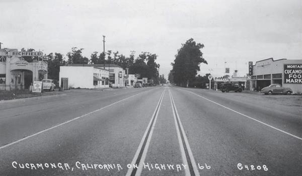 black and white c.1942, view eastwards along Route 66 in Cucamonga, gas station left, Bank further ahead, cafe and Texaco right, trees
