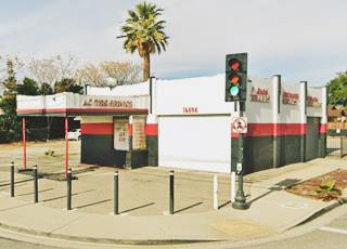 white and red former gas station, box canopy over empty pump islands, on a corner, 2 service bays on facing each street
