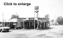 Danby gas station 1950s black and white 1950s gas station, car, DANBY written on flat canopy, sells Chevron gas