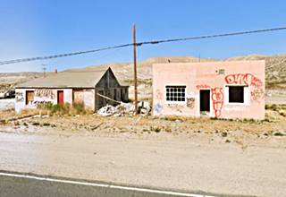 two vacant buildings, one gable roof, the other flat roofed, covered with graffiti