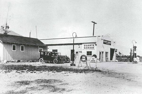 1930s Duarte Garage, Duarte CA Route 66 black and white 1930s. gable roof building with 1930 cars on the left, masonry building, a garage with gas pumps DUARTE GARAGE on the sign, to the right