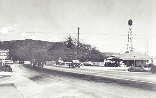 Eaton’s Santa Anita Drive In c1940, Arcadia CA black and white, c1940 mountains in the distance, highway on the left, cars. To the right a drive in with steeple over 8-sided drive in area, sign reads EATON’S