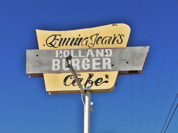 pale yellow sign atop a post reads EMMA JEAN’S CAFE - HOLLAND BURGER