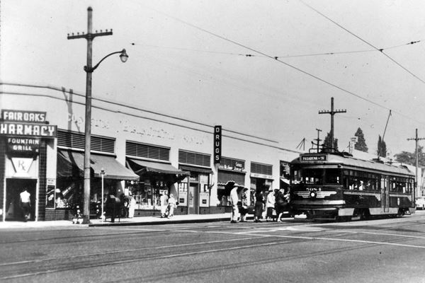 Fairoaks Pharmacy c.1950s. South Pasadena CA Route 66 black and white 1950s, corner building, people taking streetcar on the right. Fairoaks Pharmcacy written over corner entrance