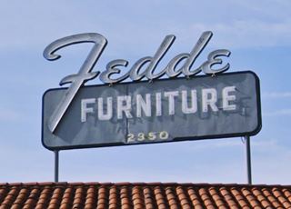 neon sign blue background rectangular, white letters in it spell FURNITURE, in script, word FEDDE written sitting on the panel