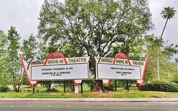 Azusa Foothill Drive-In Theater neon sign on Route 66 color, 2024, neon sign with two panels facing east and west in pale yellow with black letters, above it says FOOTHILL DRIVE IN THEATER in black with a red strip waving around it