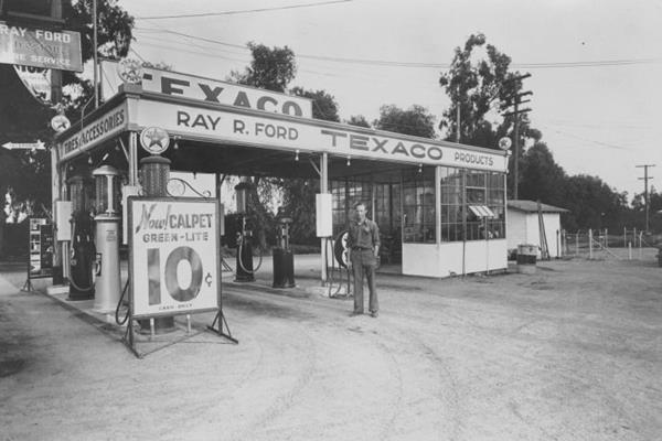 black and white c.1934, Ray Ford by Texaco gas station, woodframe, flat canopy over 2 pump islandss, signage