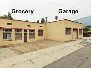 flat roof building, tiles along cornice edge. Door flanked by windows to the left. Garage with service bay right. Street runs in front of it