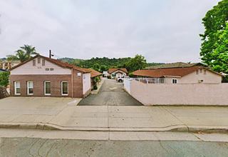 Gilpin Motel Glendora color, 2020s gable roofed buildings on both sides of a central driveway, hills beyond, a former motel