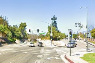Route 66 underpass Glendora nowadays color, 2020s cars, highway with median with trees dips into underpass, road to the right, concrete containing walls on tunnel