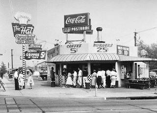 The 1st Hat diner, 1951, Los Angeles CA black and white photo 1951, corner shop with people buying food, neon sign to the right, CocaCola and Pastrami written on roof billboard