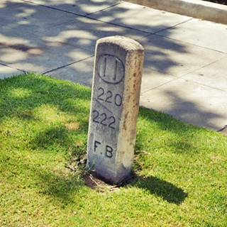 concrete marker on grass patch on sidewalk with numbers inscribed on it