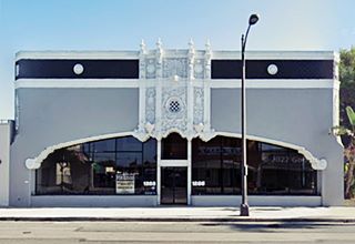 semi eliptic window on ornate gray building, one story, street runs in front