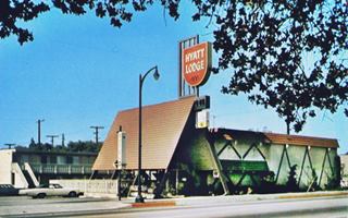 color postcard late 1960s. Steep roofed canopy over entrance, motel with units at the back 2 stories. Car parked left. Route 66 in front. Sign over canopy in red and white says: HYATT LODGE