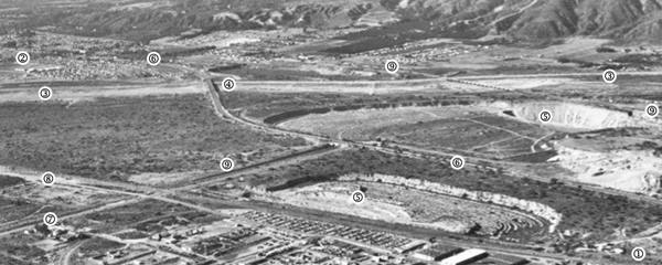 black and white aerial photo, detail showing mountains in the distance, river running left to right, highway crossing it, some streets, Duarte upper left, gravel pits and Route 66