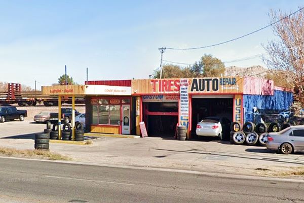 yellow red and blue former 1950s gas stations, now tire shop. Flat canopy, 2 service bays, corner office, pump islands