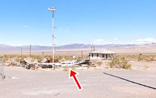 rubble and burned remains, hills in the distance, pole of neon sign, empty