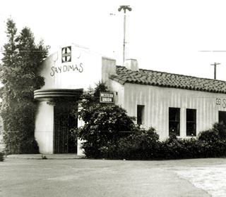 Railway Depot in San Dimas 1930s black and white single story Spanish Mission style building, bushes by it sign reads San Dimas, a railway depot