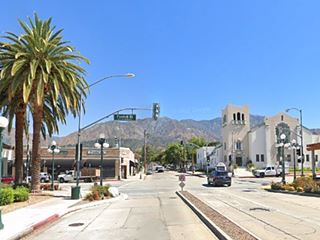 intersection of avenues, palm trees left, store across the street, church to the far right, shop to the right, mountains beyond