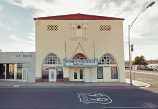 2 story building with a Spanish Air to it, Route 66 in front, shield painted on road