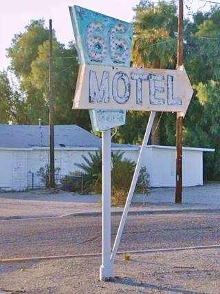 1950s neon sign with trapezoidal green panel and orange arrow in a triangular steel frame