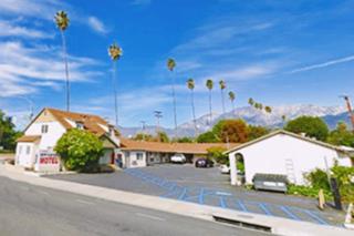 New Kansan Motel Cucamonga Rte 66 nowadays two story motel, motel, seen from US66, palm trees lined on the left, mountains beyoned red tiled roofs
