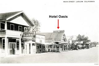 Oasis Hotel in Ludlow CA woodframe buildings along a Main street, inn, stores and one with HOTEL OASIS written on roof black and white Ludlow c.1920s