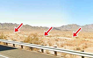 US66 alignment north of Needles CA Original dirt road in a desert, seen from the freeway, hills beyond