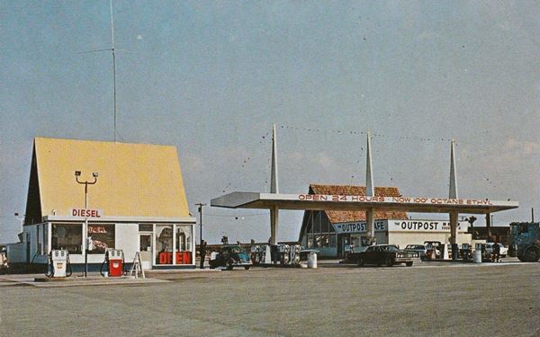 gable roofed cafe, cars, wing shaped canopy over gas pumps, 1960s color photo