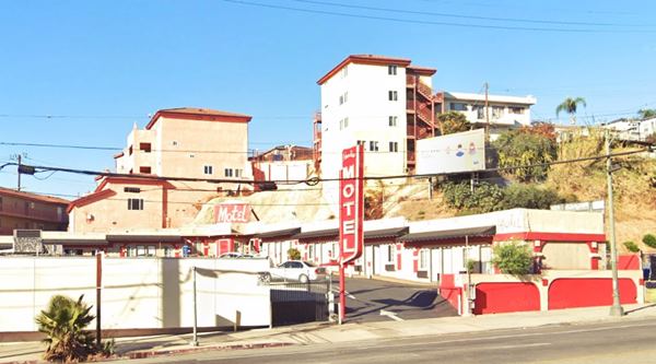 The Paradise Motel nowadays US66 LA red neon sign white letters reads PARADISE MOTEL. L layout with units with flat roofs seen from an avenue