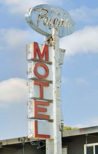 neon sign topped with pale blue faded oval reads THE PASADA, below white panels vertically spell with red letters; MOTEL