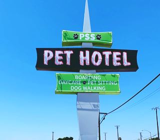 neon sign with three panels upon a spike shaped column announcing a Pet Hotel in green, white and black colors