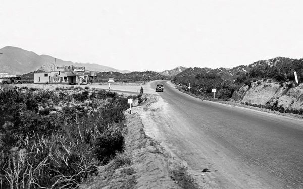 1930s Pine Lodge Service Station US66 in Cajon Junction black and white, highway to the left, and a junction beyond, gas station on the corner c.1930s
