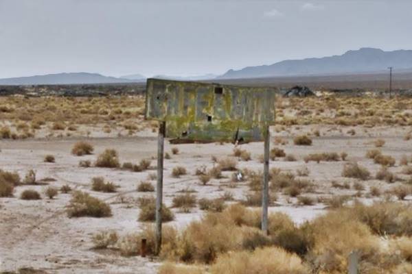 sun bleached green sign in the desert, faded and peeling with white letters