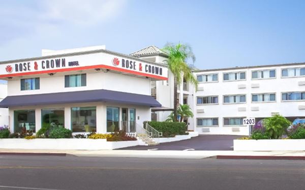 3 story building, white stucco, 2 story flat roofed office, sign reads ROSE AND CROWN, a hotel seen from Colorado Blvd.