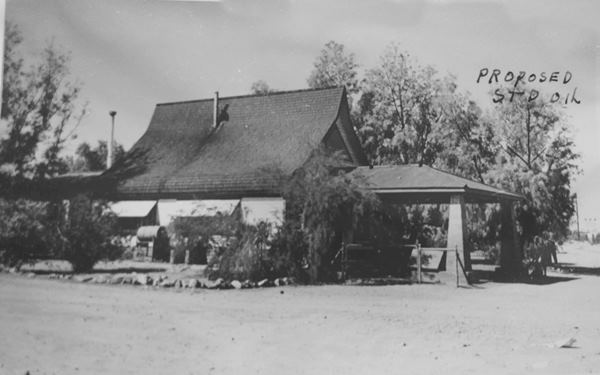 Ski Slope house in Daggett by US 66 c.1920s black and white 1920s-30s house with barrell roof with trees around it and gravel drive