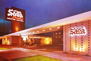 night view lit neon sign on a column atop a flat roofed building SAGA Pasadena Motor Hotel on sign. Wall to the right reads SAGA, 1960s color postcard