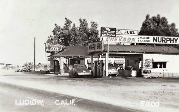 Shamrock and Chevron stations Ludlow c.1940 US 66 1930s black and white left US 66, right: two gas stations, one says MURPHY BROS Chevron, the other SHAMROCK CAFE, cars filling tank, gabled canopies, trees behind