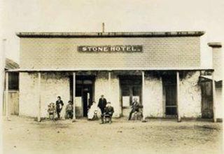 Stone Hotel c.1910 black and white early 1900s. Single story bldg. STONE HOTEL written on parapet, people under awning, dirt street in front