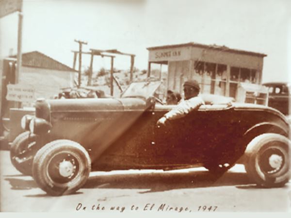 On the Way to El Mirage 1947 sepia, man and boy in an open coupe convertible dated 1947, by a building reading SUMMIT INN, other building to the left with gas pumps