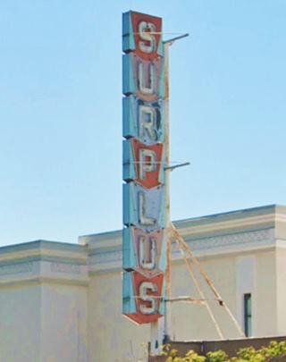 neon sign with vertical panels each holding a letter spelling SURPLUS