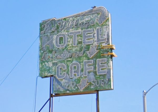Village Hotel neon sign US 66 fading peeling 1950s green neon sign with white letters and yellow details reads: THE VILLAGE HOTEL CAFE Air contidioned Chop Suey.