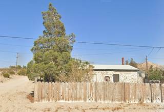 stone building, single story, pine tree left, wood fence facing highway