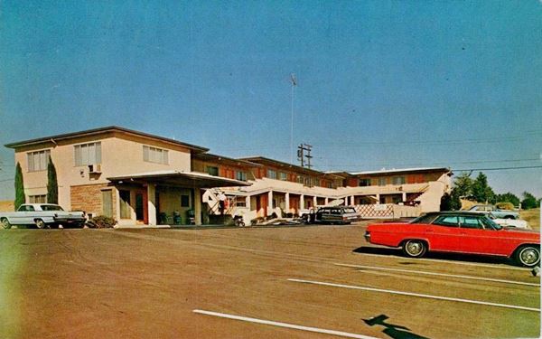 two-story building with external stairs, canopy by office and cars parked. c.1960s